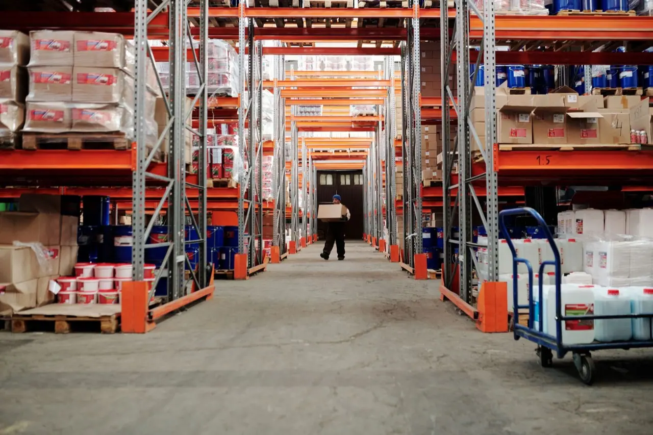 Worker carrying a box along a warehouse aisle